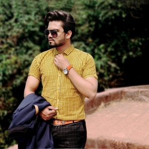 Stylish man wearing sunglasses and checkered shirt posing outdoors in Mahabaleshwar.