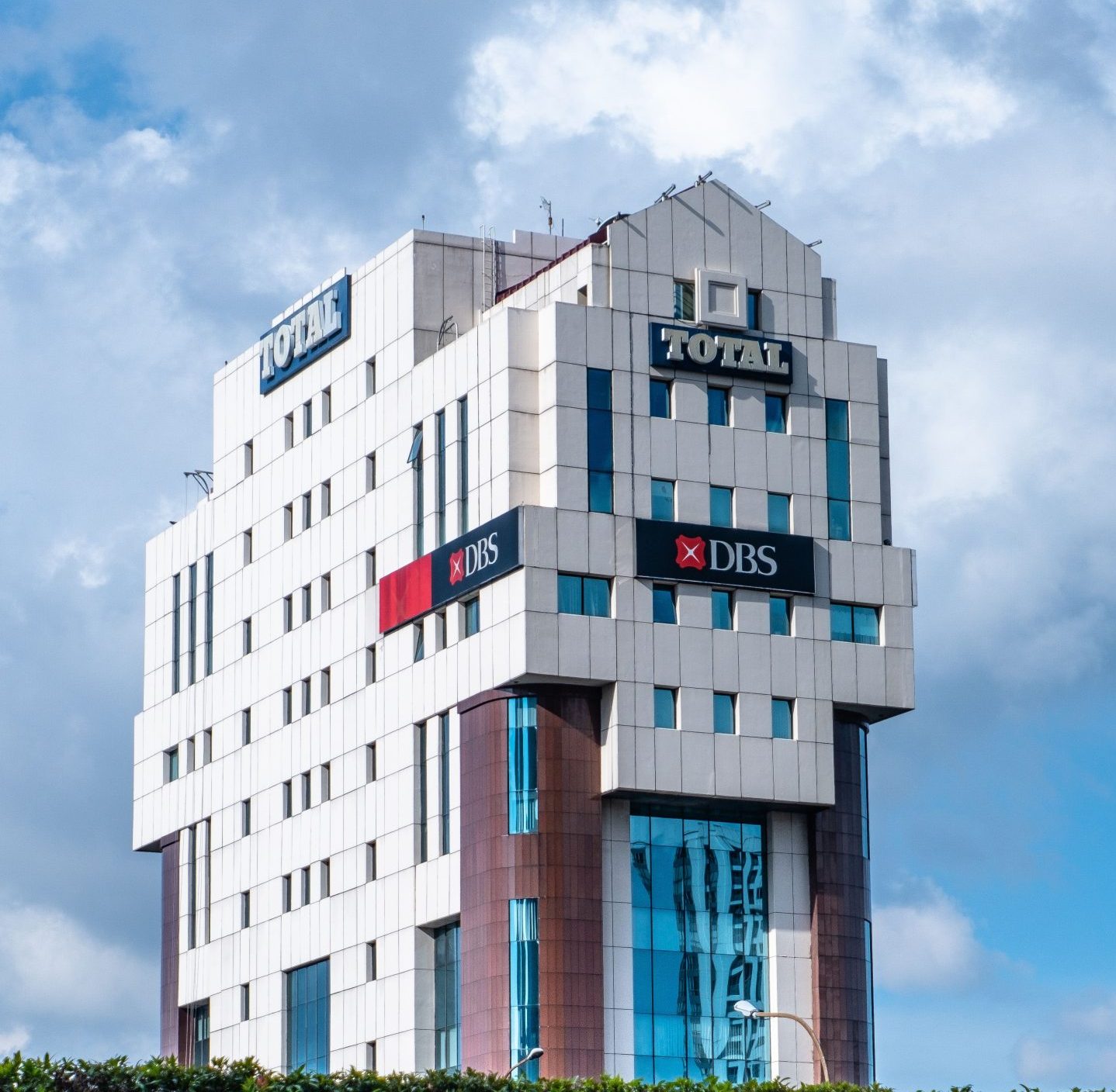 Vertical shot of a modern office building against a blue sky, showcasing exterior design.